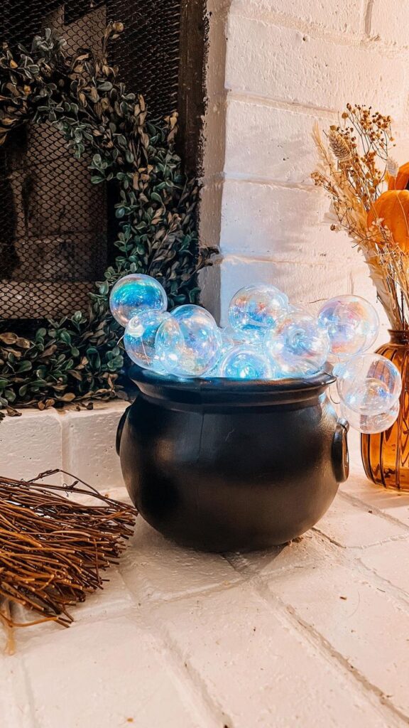 Cauldron filled with LED string lights, glowing through layers of faux spiderwebs for a mystical effect, perfect for dark corners or as a nightlight.