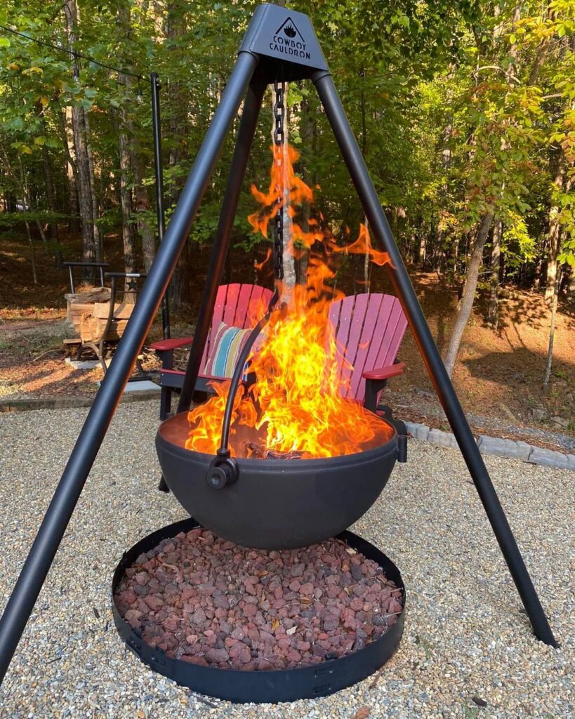 Large metal cauldron used as a fire pit, with flames or glowing stones creating a warm, spooky ambiance in an outdoor setting.