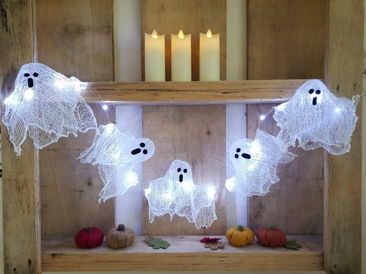 Fabric ghost garland lit up by LED lights, hanging across a doorway.