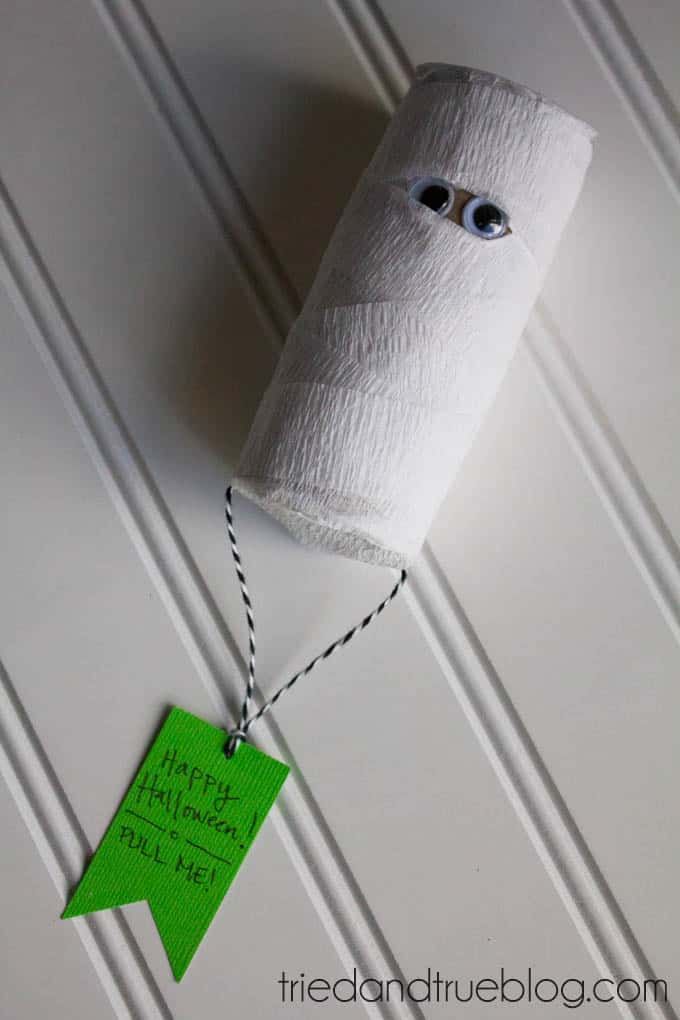 Toilet paper holder wrapped in gauze with googly eyes, resembling a mummy.