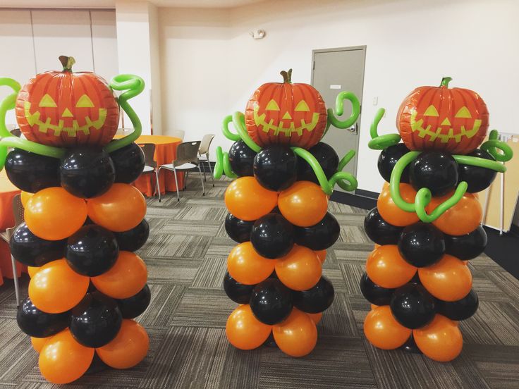 Cluster of orange balloons with hand-drawn jack-o'-lantern faces.