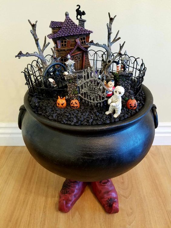 Small cauldron used as a terrarium with succulents, moss, and tiny fantasy figurines, perfect for desks or shelves.